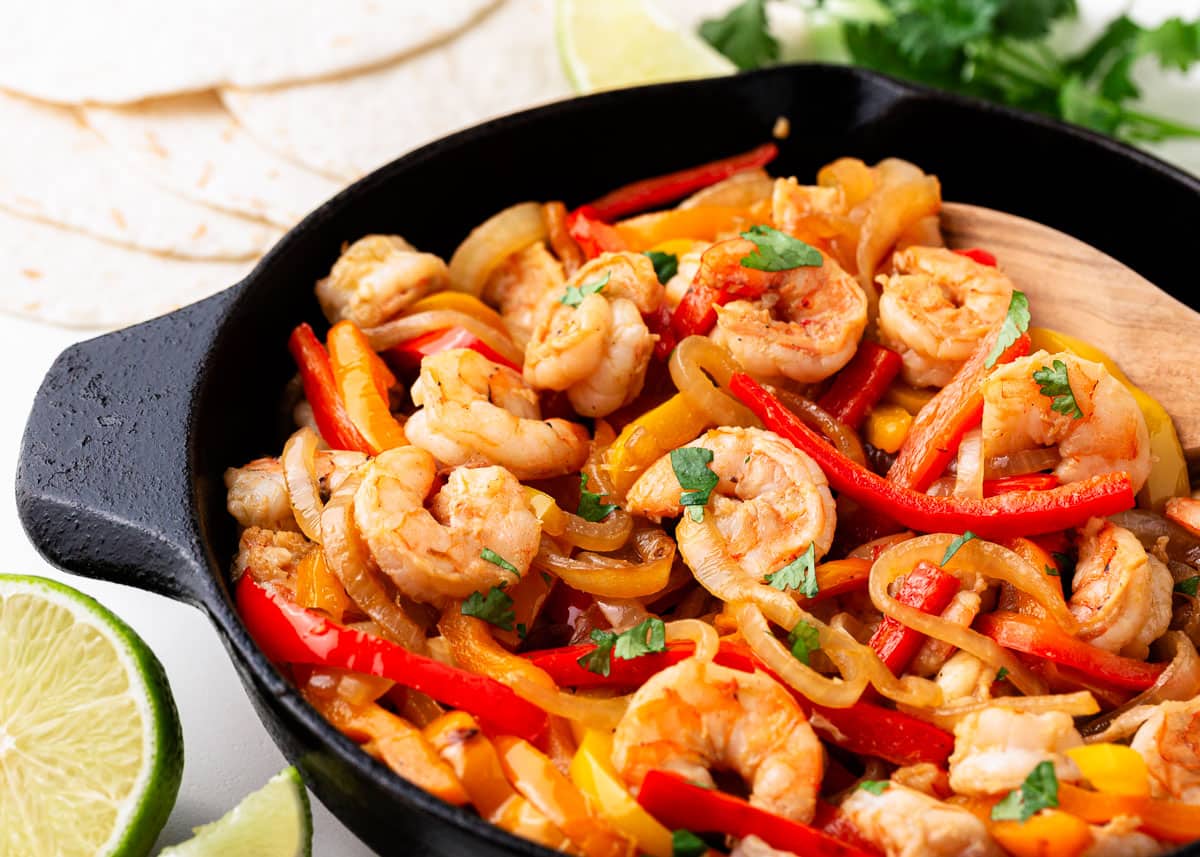 Shrimp fajitas, onions and bell peppers in a skillet.