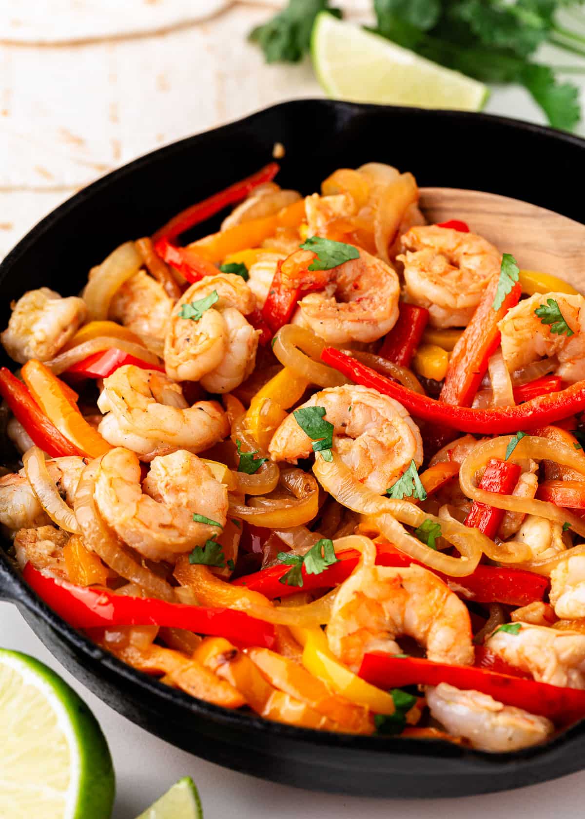 This recipe for shrimp fajitas is a one skillet dinner that is quick and easy to make with fajita marinated shrimp and sauteed peppers and onions. This sizzling dish is so flavorful! Shrimp fajitas and peppers in a skillet.