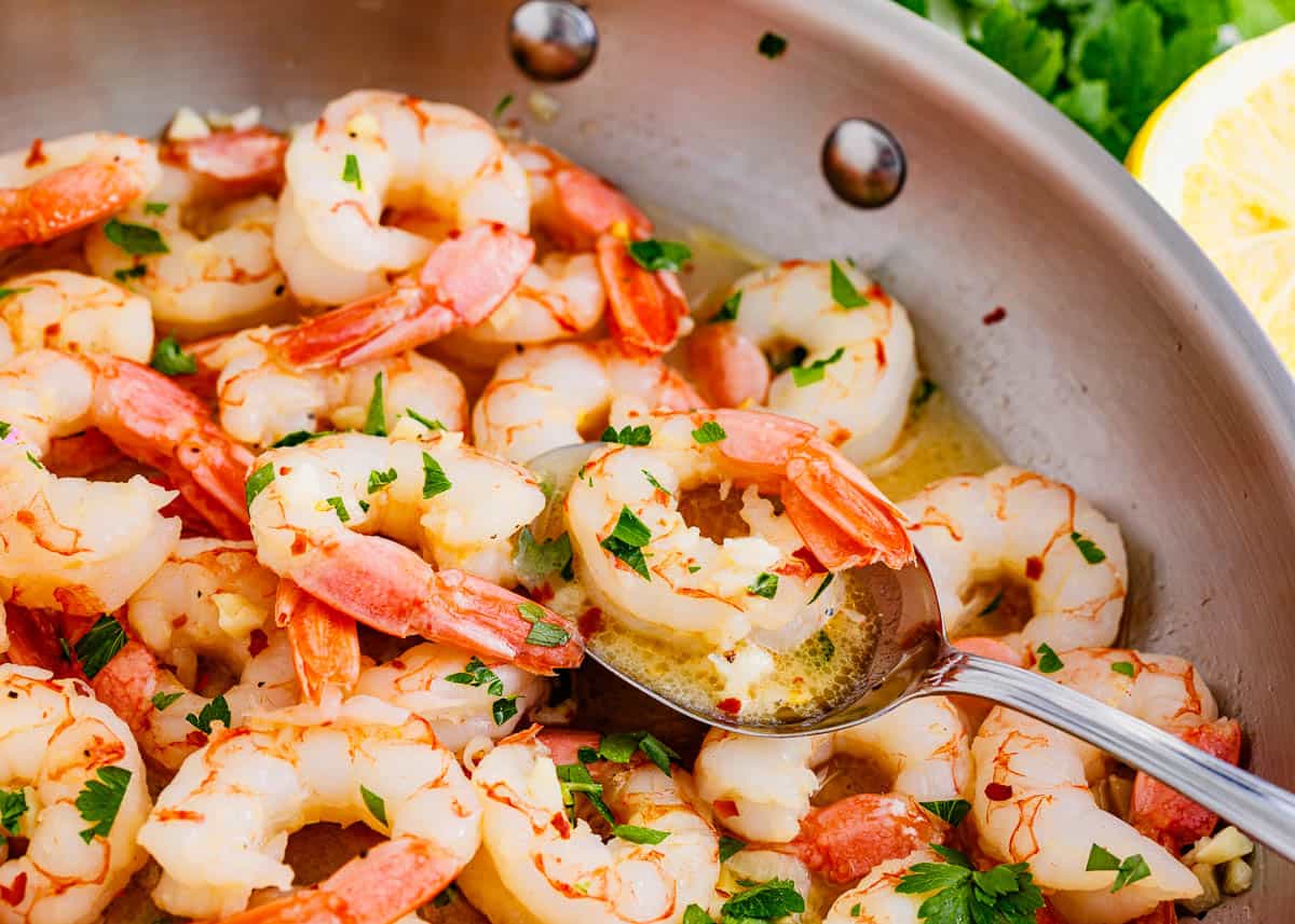 Shrimp scampi cooking in a skillet.