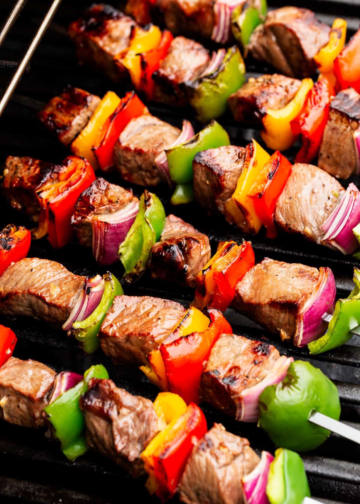 Steak kabobs cooking on a grill.