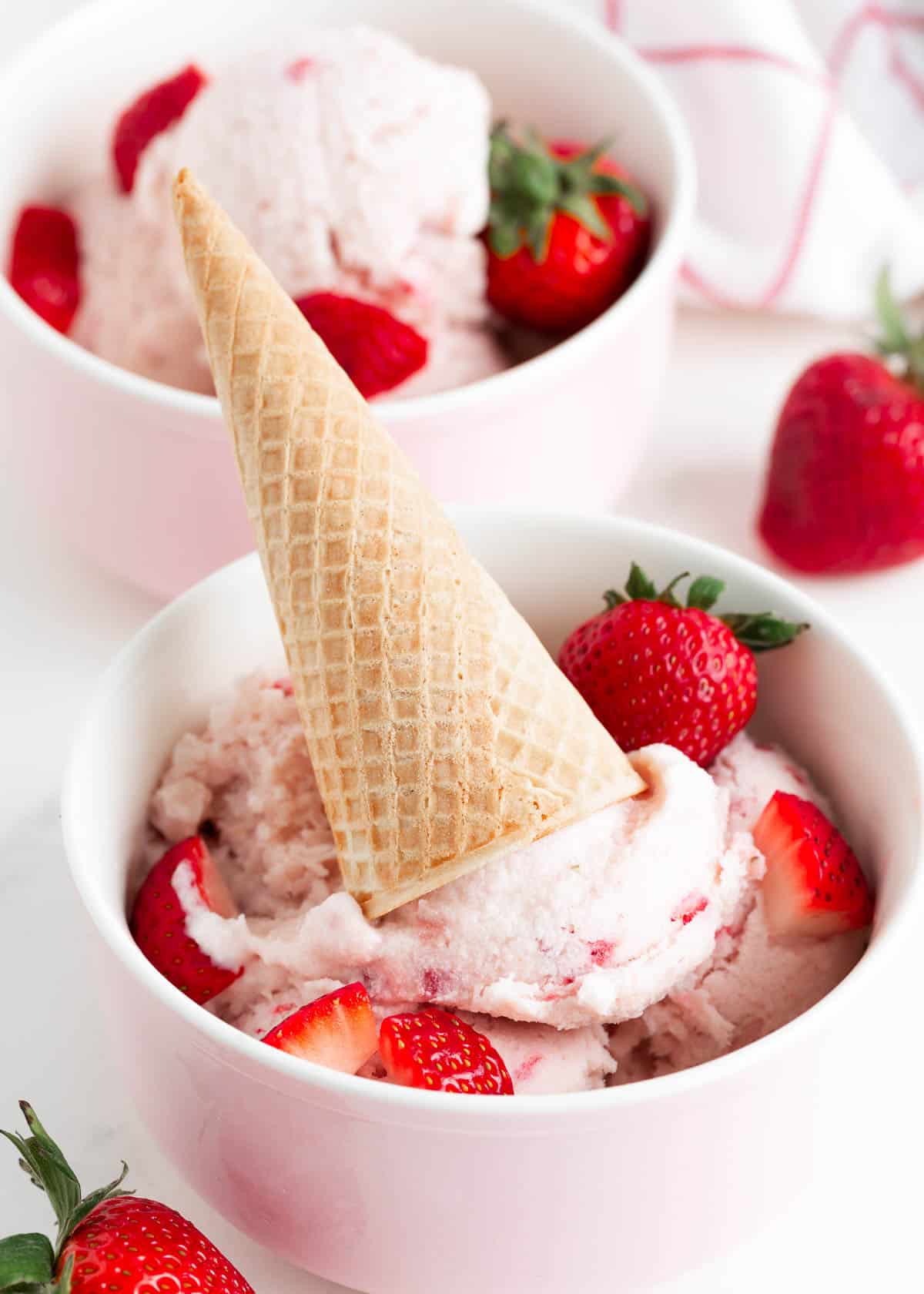 Strawberry ice cream in a bowl with cone.