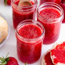 4 jars of strawberry jam on counter.