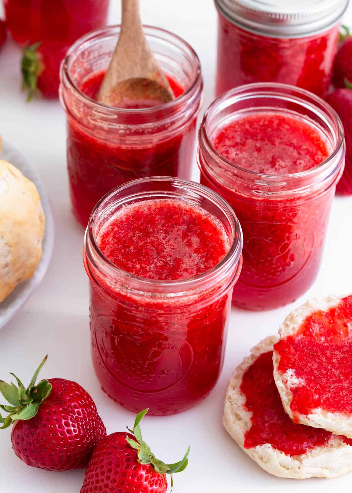 4 jars of strawberry jam on counter.