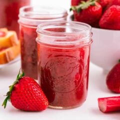 No pectin strawberry rhubarb jam in jars on counter with fresh rhubarb and strawberries on counter.