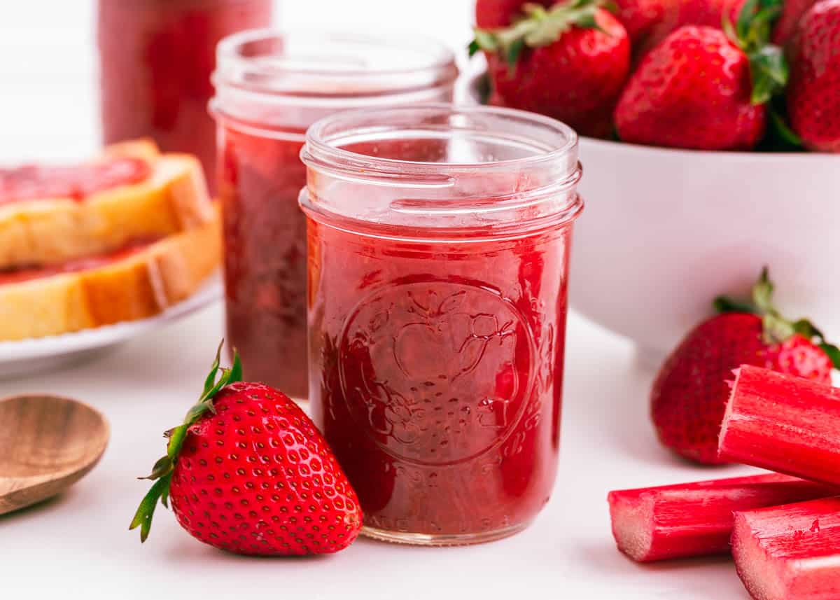 Strawberry rhubarb jam in jars on counter.