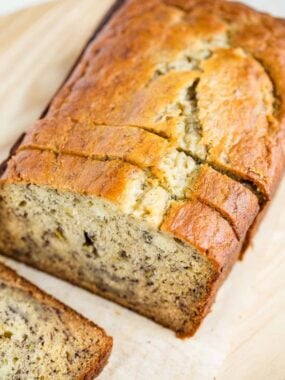Moist banana bread sliced on a wooden cutting board
