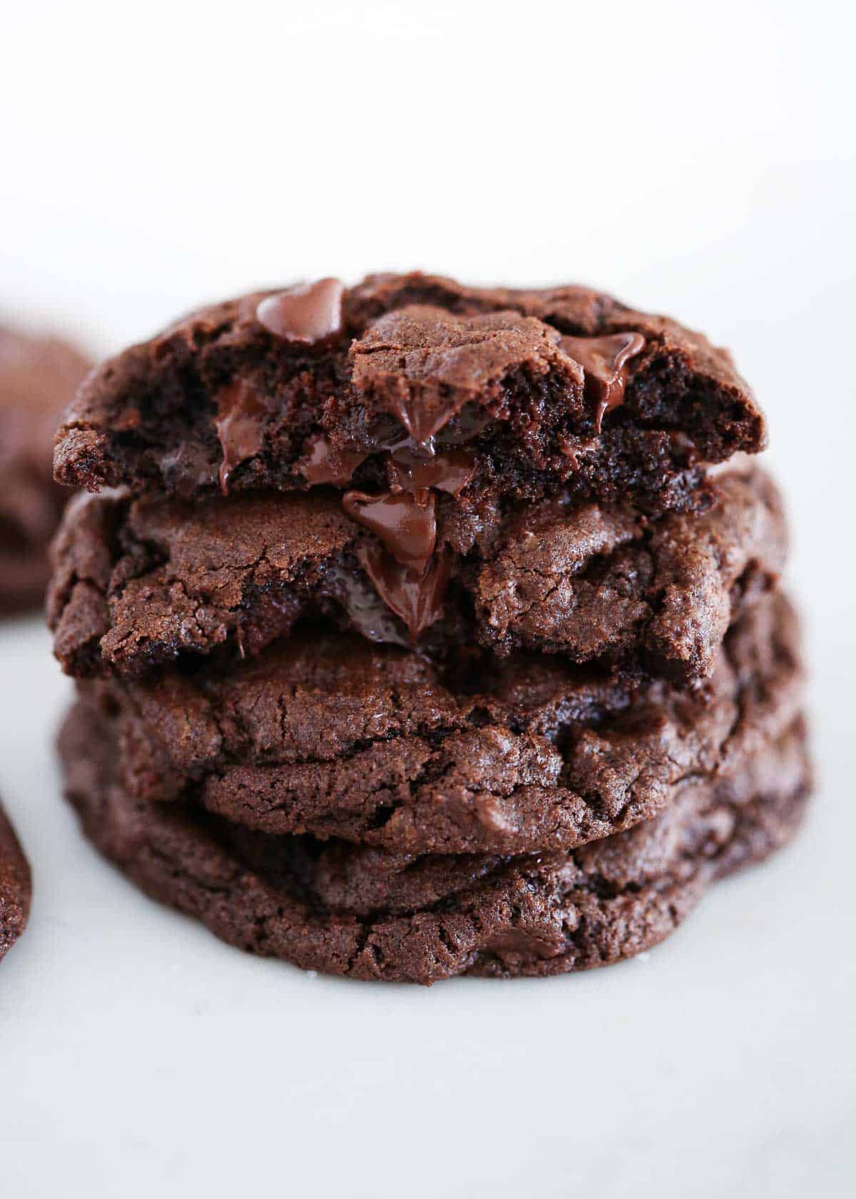 Stacked double chocolate chip cookies on a marble countertop.