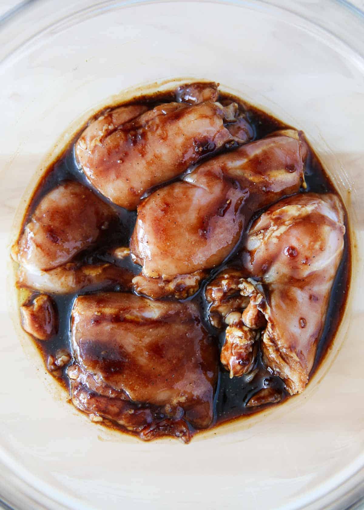 Grilled chicken thighs marinating in a bowl.