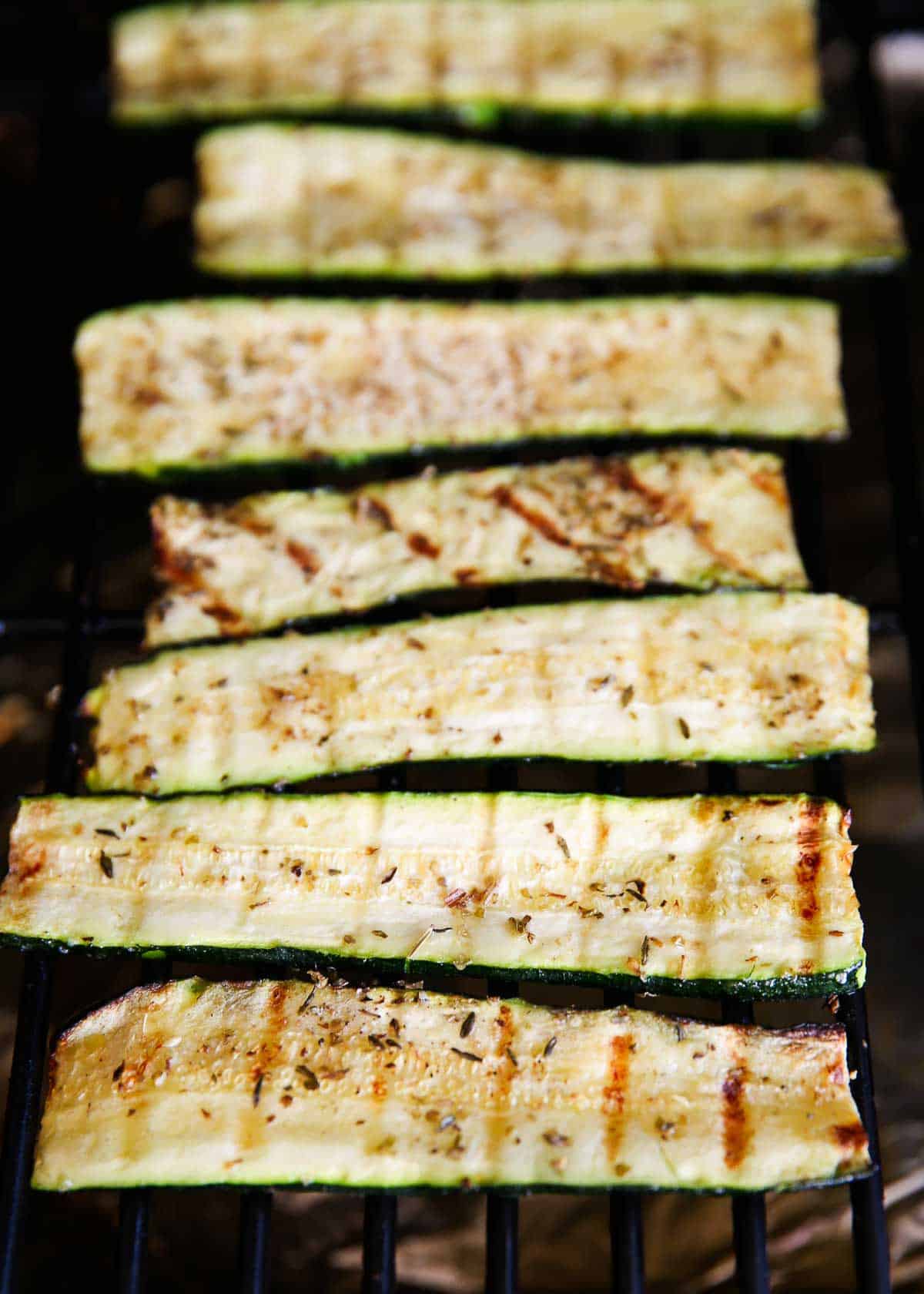Grilled zucchini cooking on grill.
