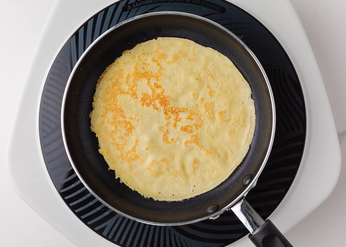 Thin crepe cooking in a nonstick skillet until lightly golden and set.