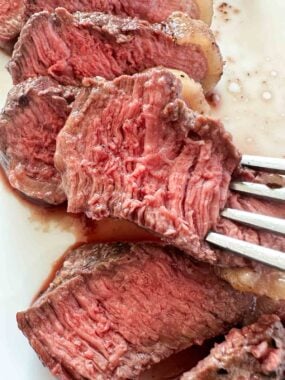 Slice of tender sirloin steak with a fork lifting a piece up to show juicy results.