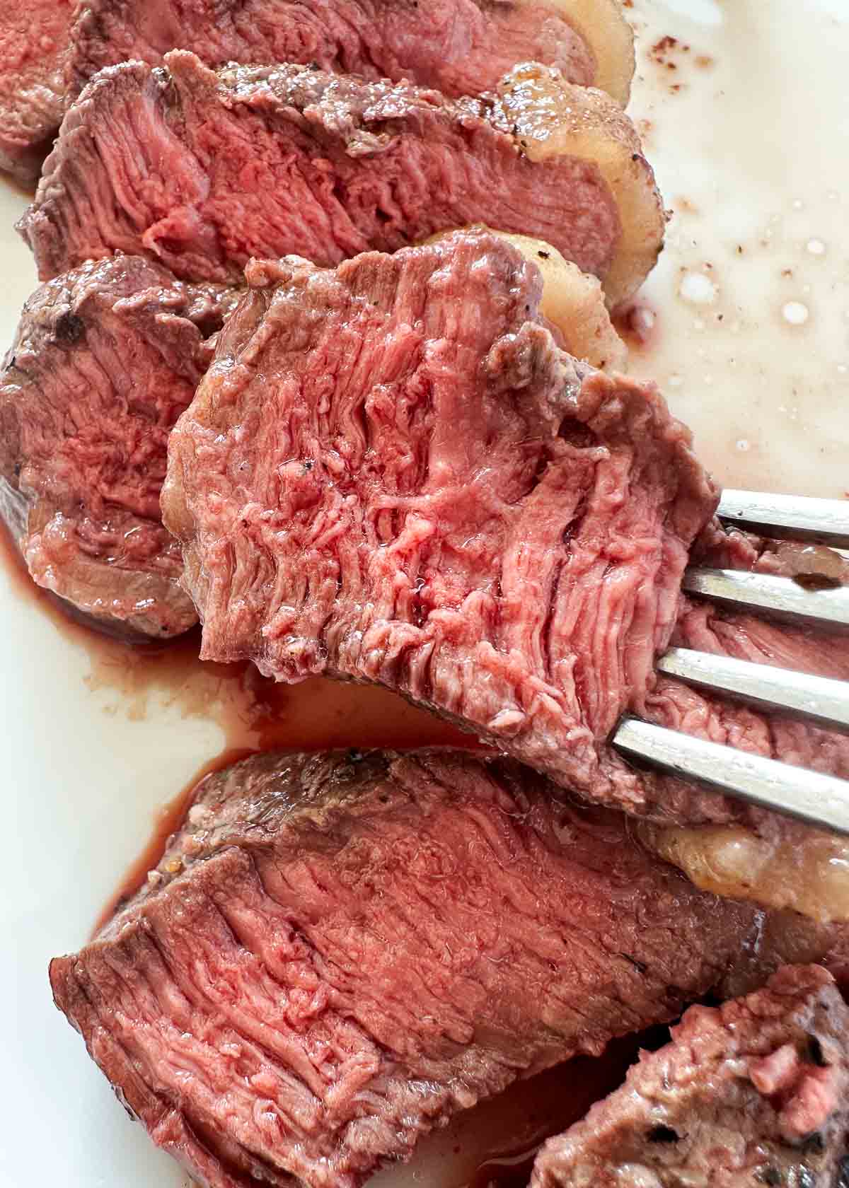 Slice of sirloin steak with a fork.