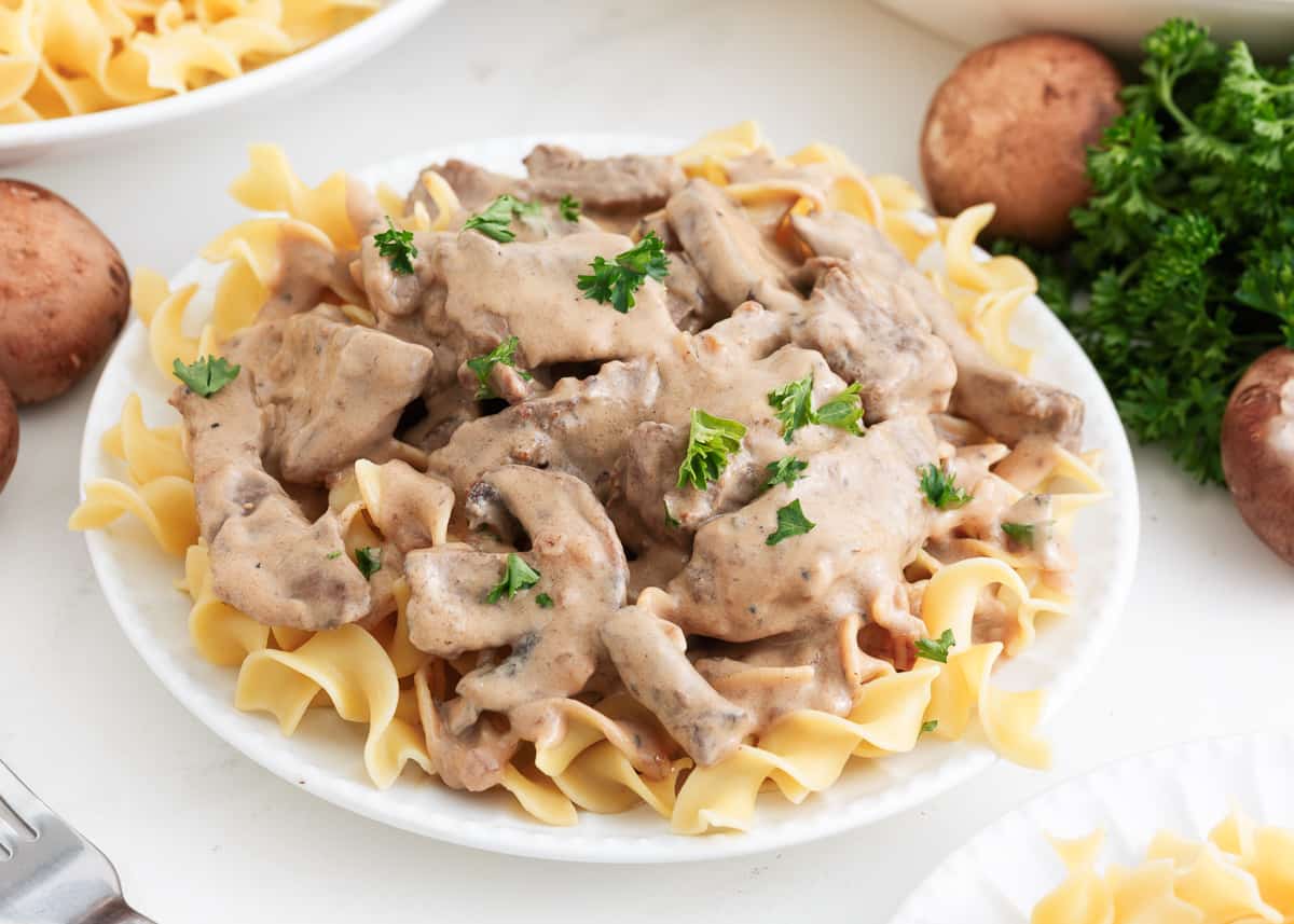 Beef stroganoff over noodles in a bowl.