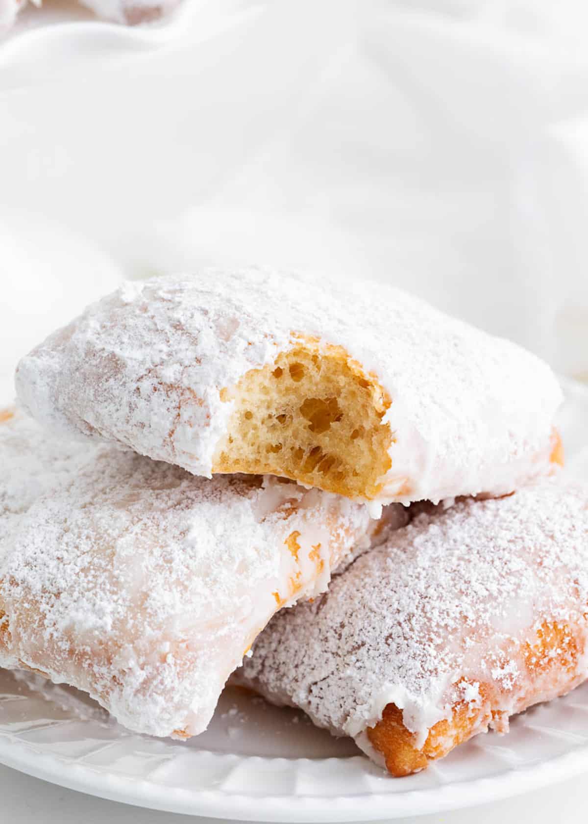 Beignets stacked on a white plate.