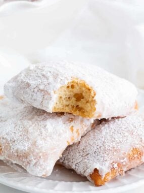Beignets stacked on a white plate.