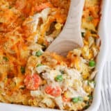 Spoonful of chicken noodle casserole in a white baking dish.