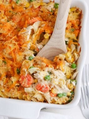 Spoonful of chicken noodle casserole in a white baking dish.