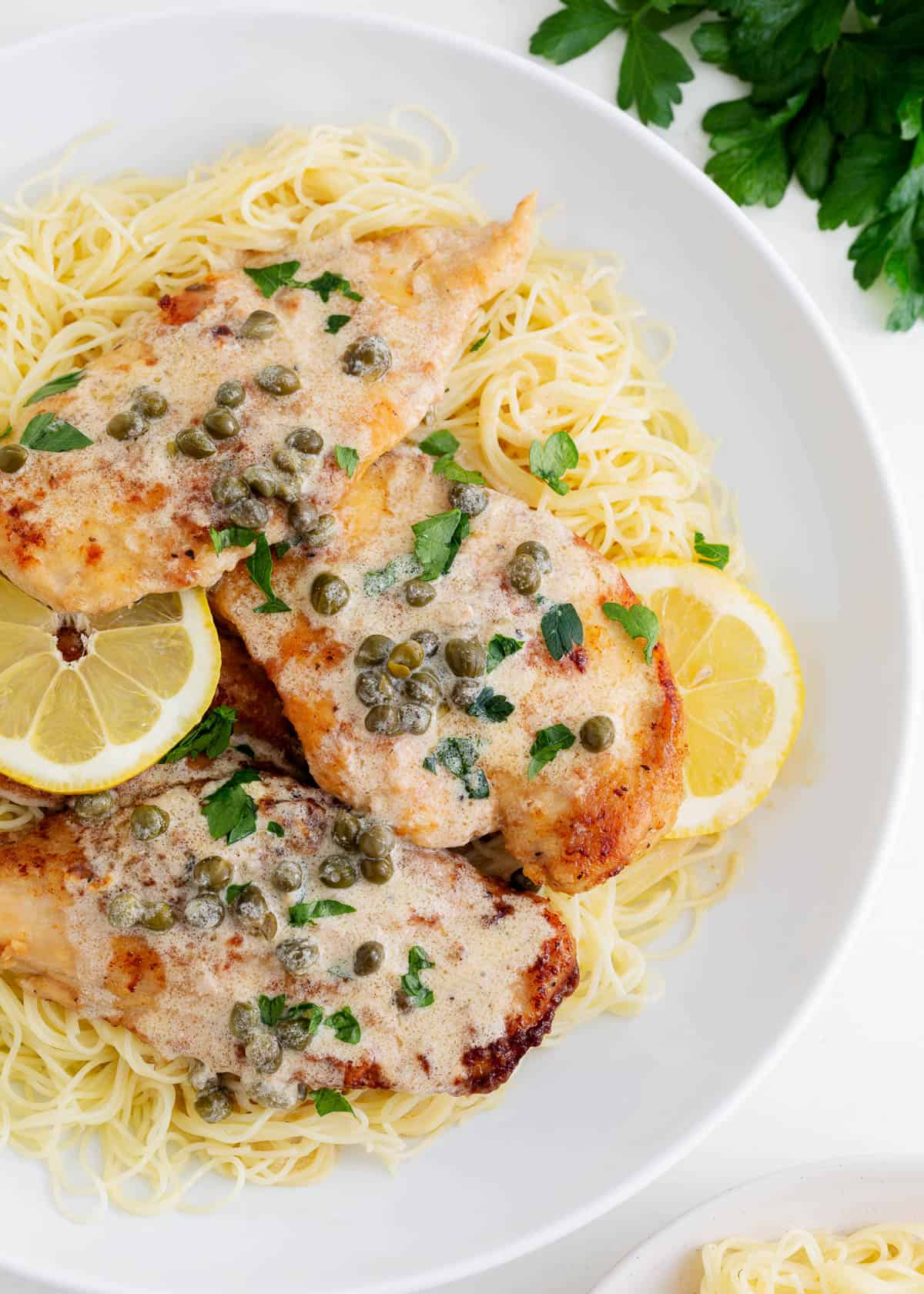 Chicken piccata and angel hair pasta in a bowl.