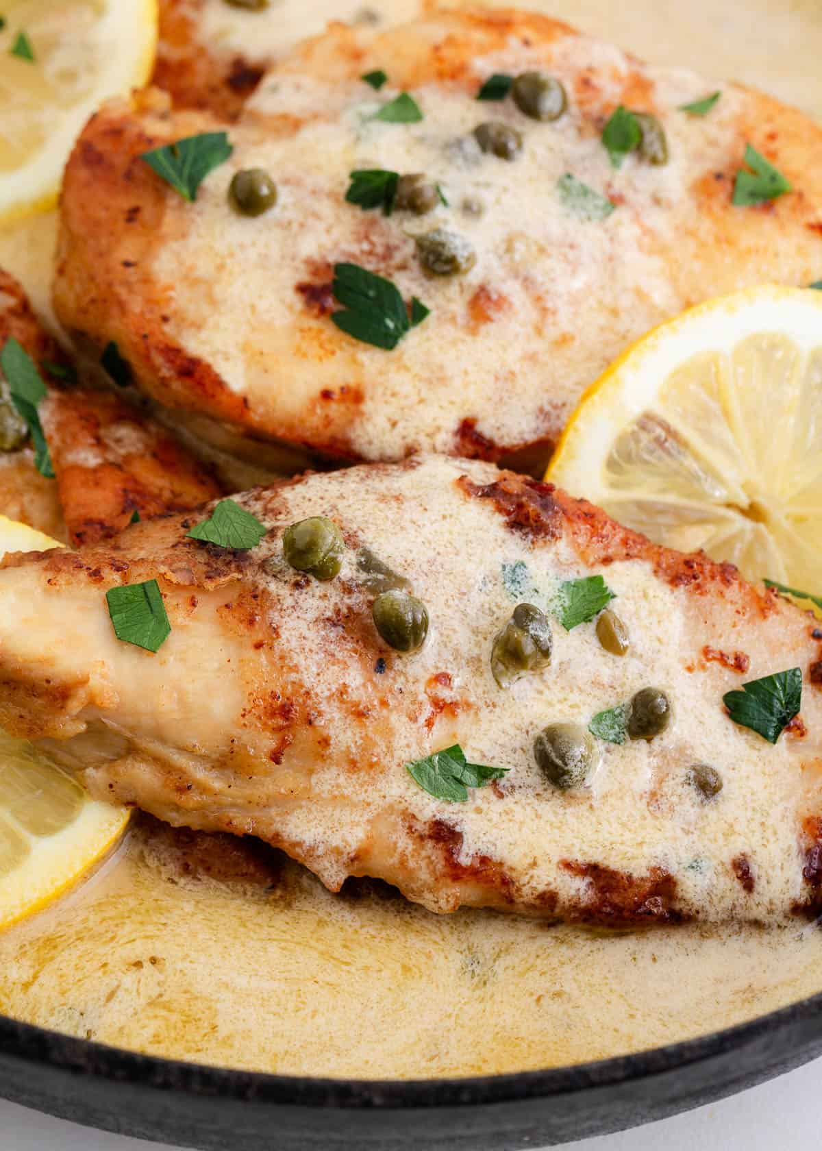 Chicken piccata cooking in a skillet.