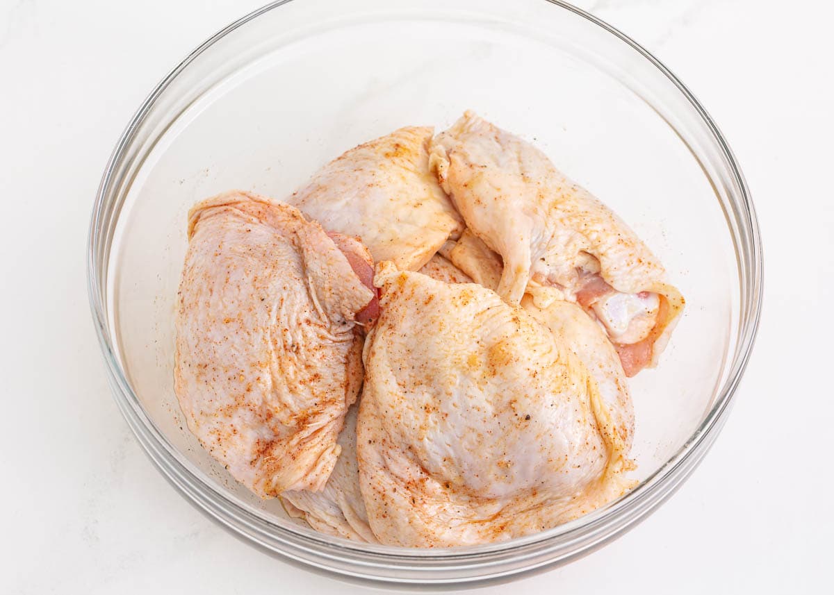 Raw chicken in a bowl with dry rub on it.