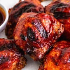 Grilled BBQ chicken thighs glazed with sticky barbecue sauce and served with extra sauce for dipping.