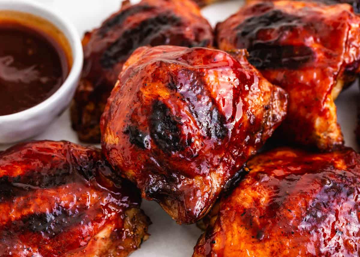 Grilled BBQ chicken thighs glazed with sticky barbecue sauce and served with extra sauce for dipping.