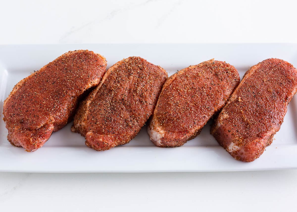 Pork chops seasoned with dry rub and resting on a plate.