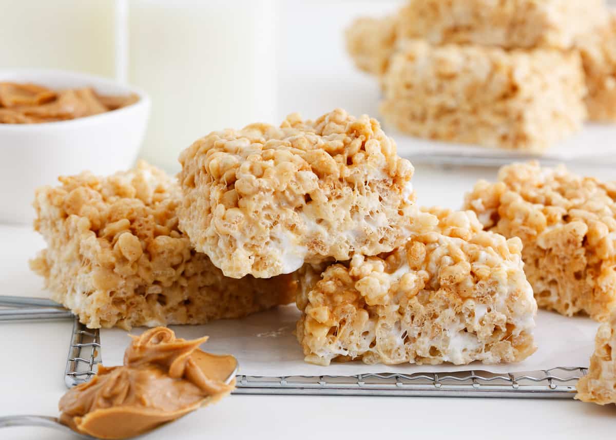 Gooey, sweet, crispy, and chewy peanut butter rice krispie treats are as simple to make as the original, but with a nutty twist! Made with just 4 ingredients, these sweet treats are a must-make simply just because you can! Stack of peanut butter rice krispie treats on metal rack.
