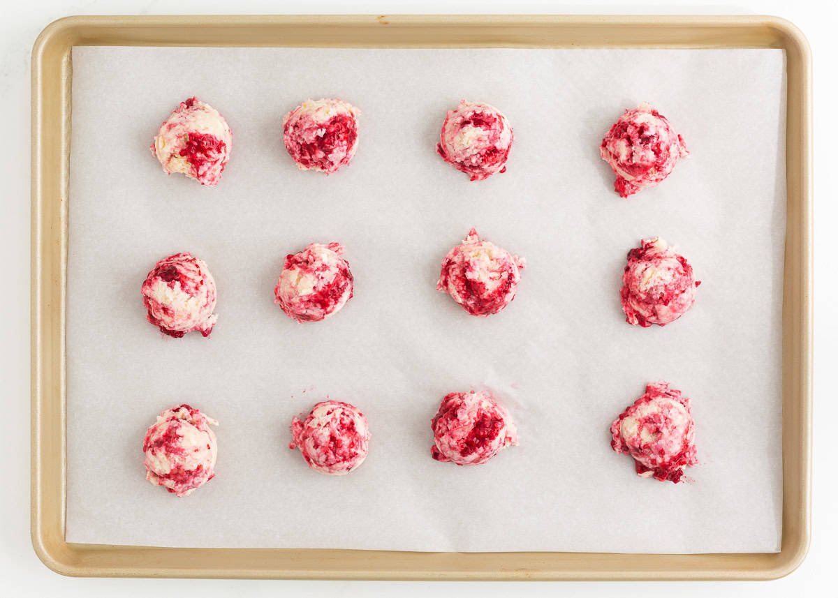 Unbaked raspberry cookie dough on parchment lined baking sheet.
