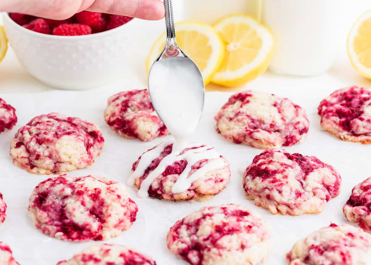 Raspberry cookies being drizzled with glaze.