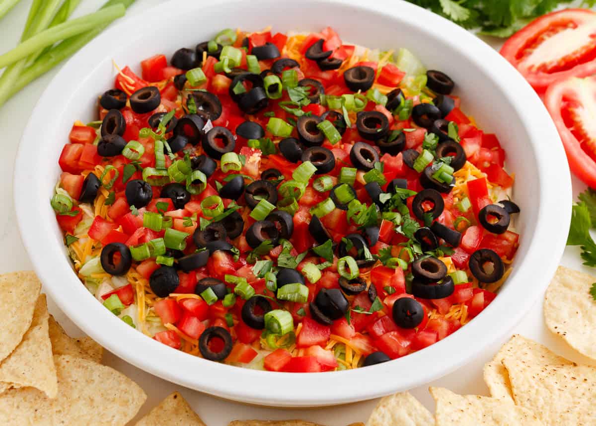 Taco dip in a white dish with tortilla chips.