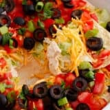 Dipping a tortilla chip into taco dip with cream cheese.