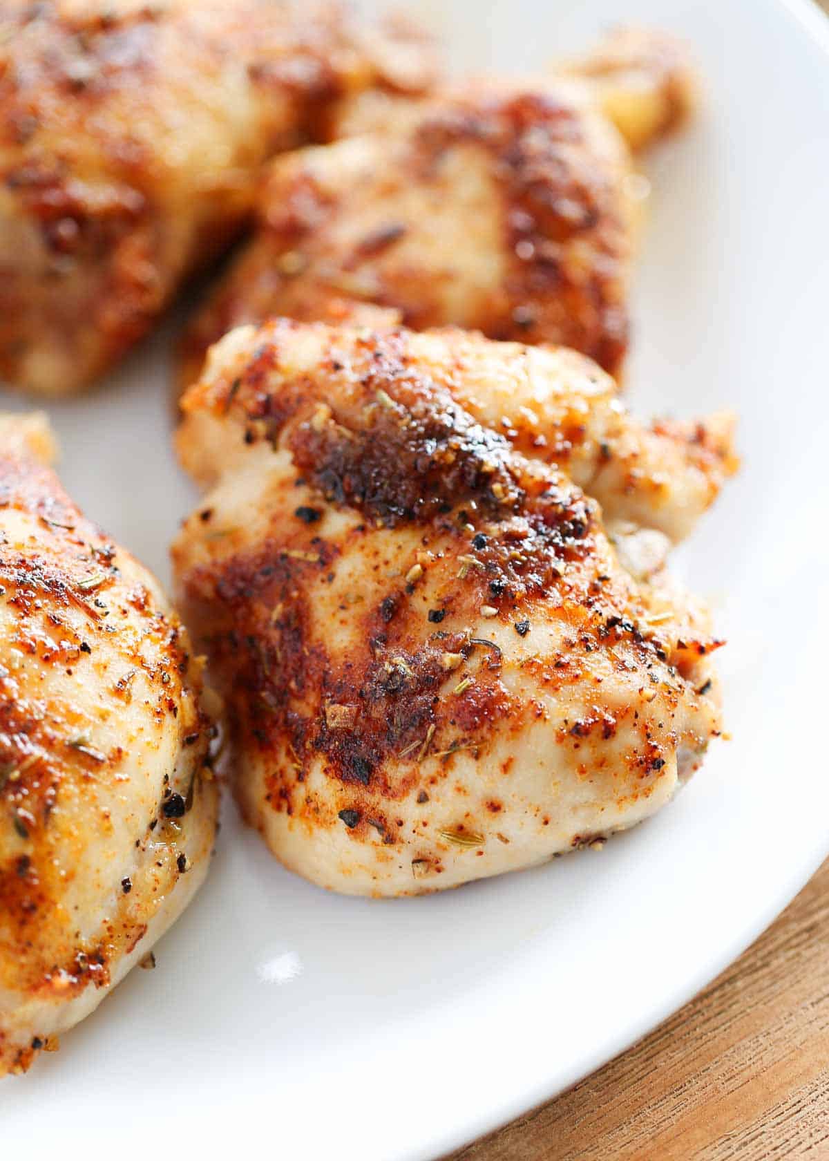 Baked chicken thighs on a white plate.