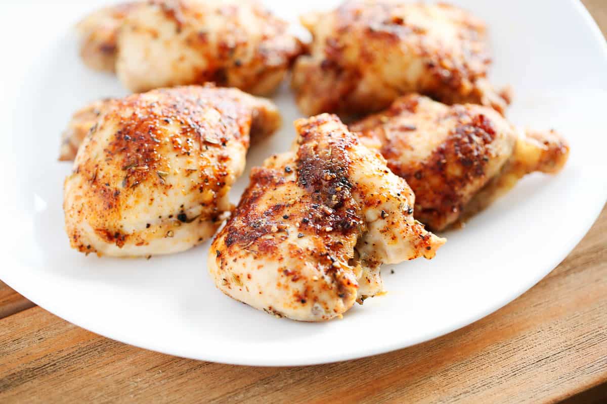 Baked chicken thighs on a white plate.