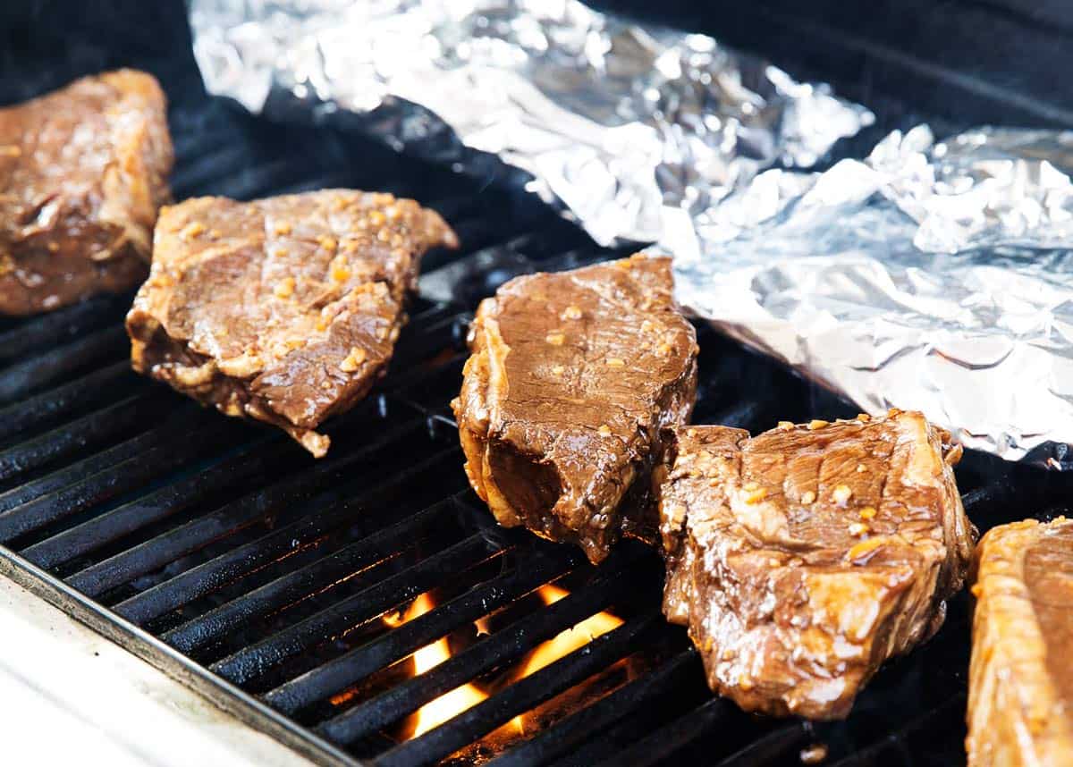 Steaks cooking on a grill. 