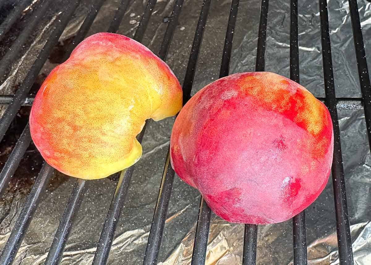 Grilled peaches cut side down on grill grates.