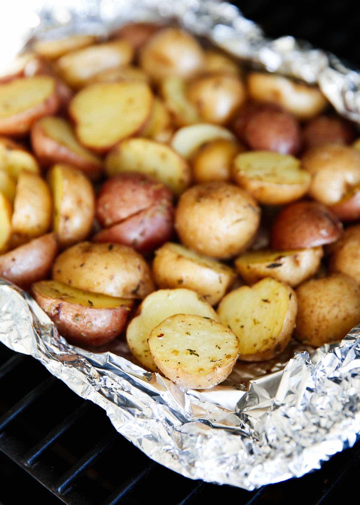 Grilled potatoes in an open foil pack on grill.