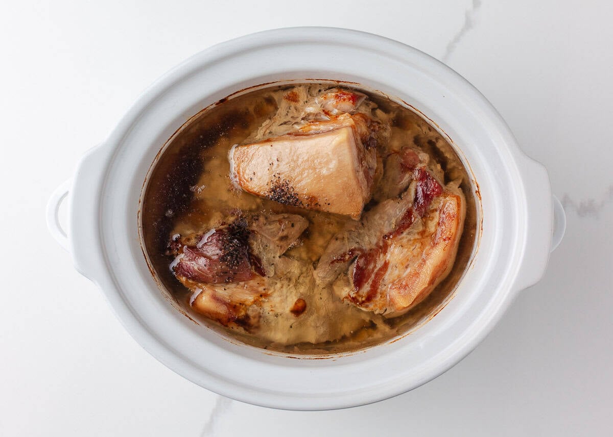Slow cooked pork shoulder in a slow cooker, tender and ready to be shredded for BBQ pulled pork sandwiches.