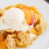 Peach dump cake in a bowl with ice cream.