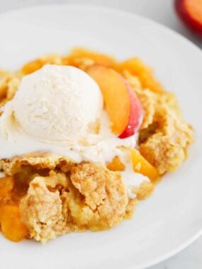 Peach dump cake in a bowl with ice cream.