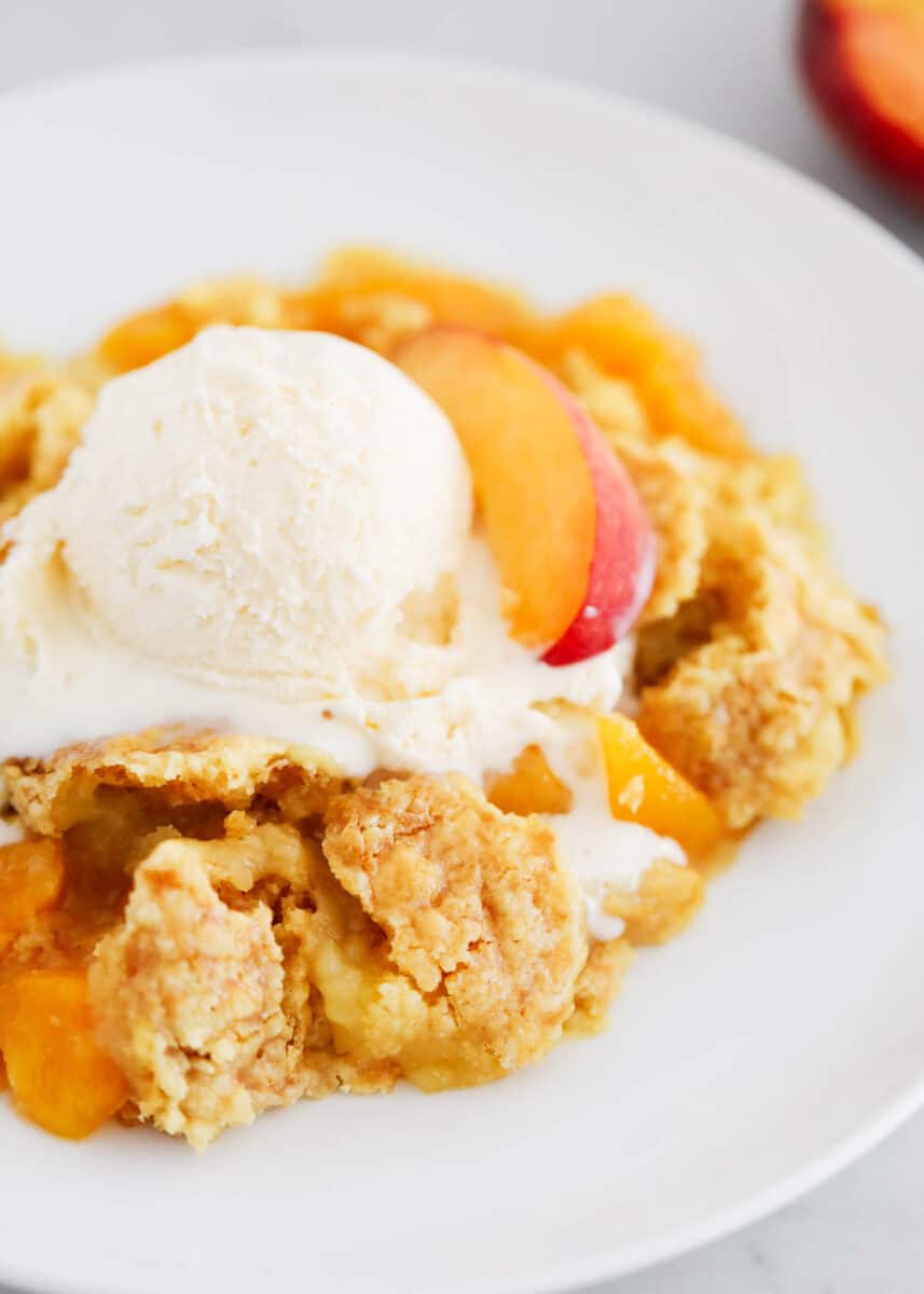 Peach dump cake in a bowl with ice cream.
