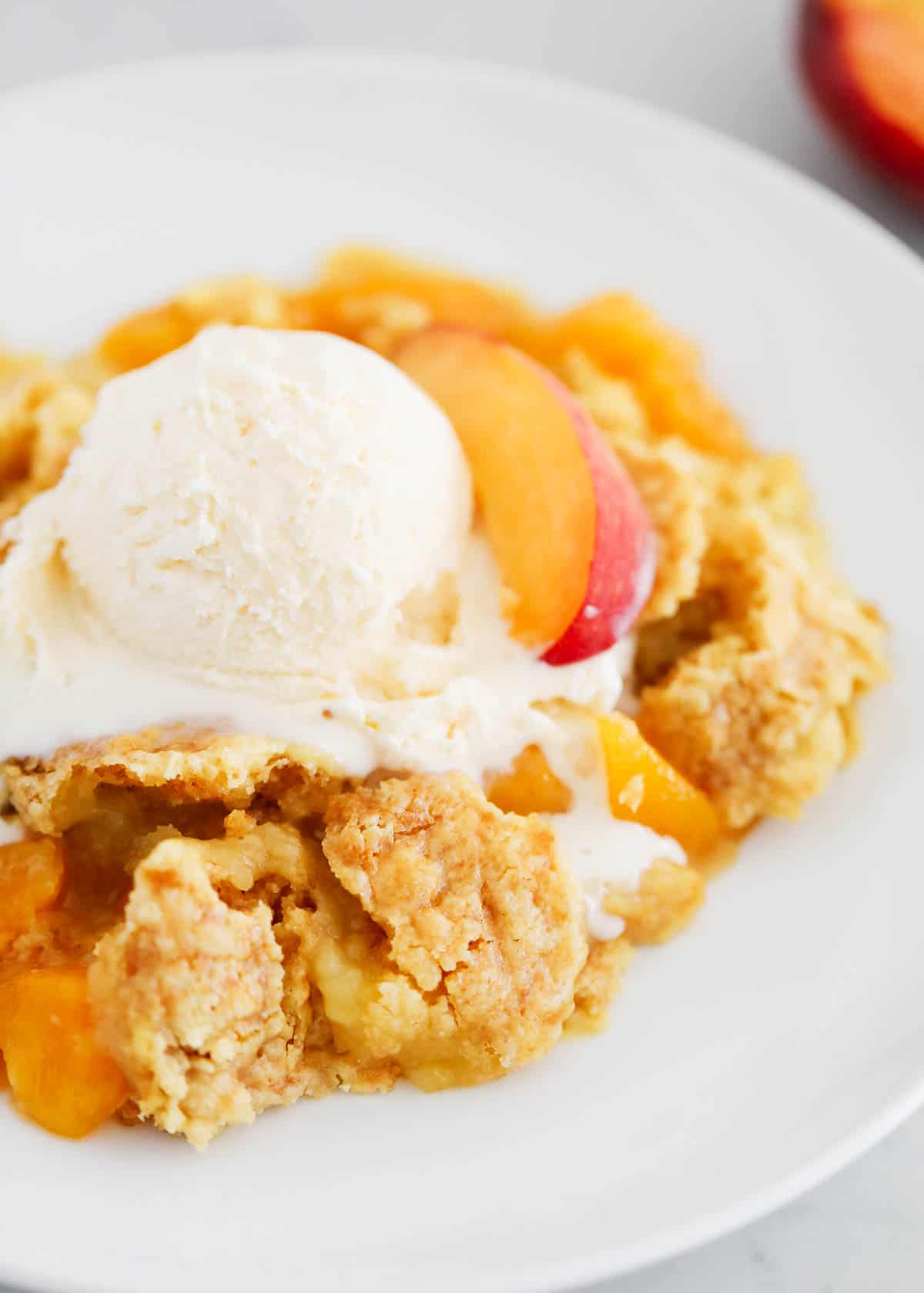 Peach dump cake in a bowl with ice cream.