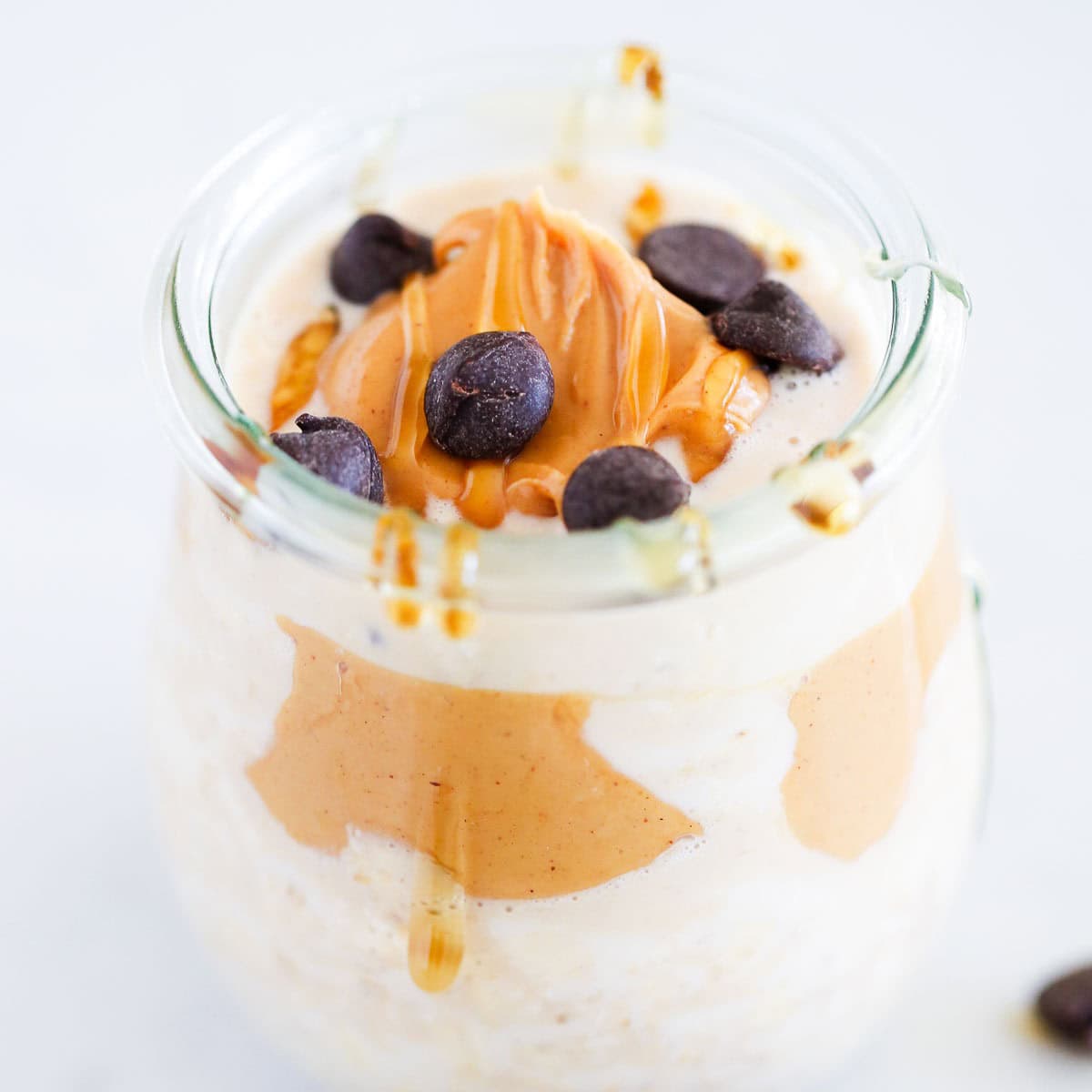 Peanut butter overnight oats in a jar topped with chocolate chips, peanut butter and honey.