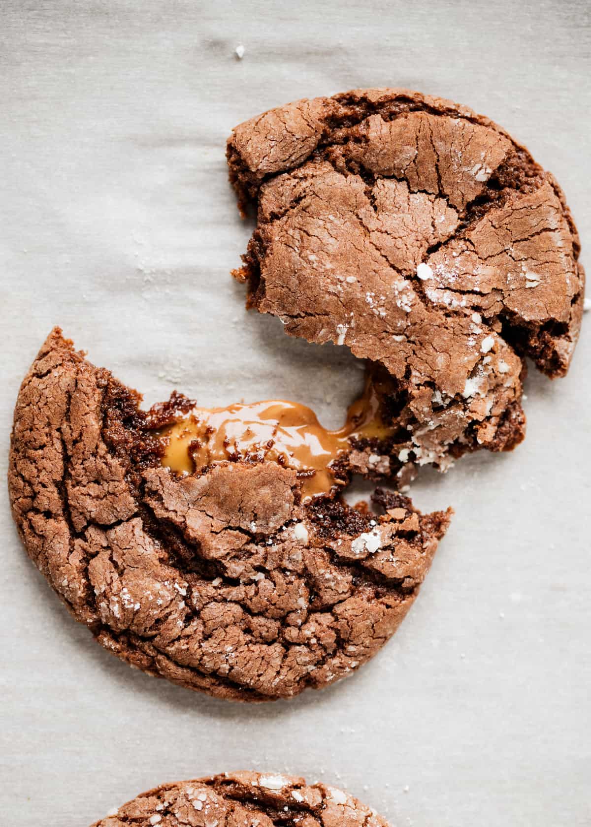 Rolo cookie split on parchment paper to show the best chocolate caramel center. 