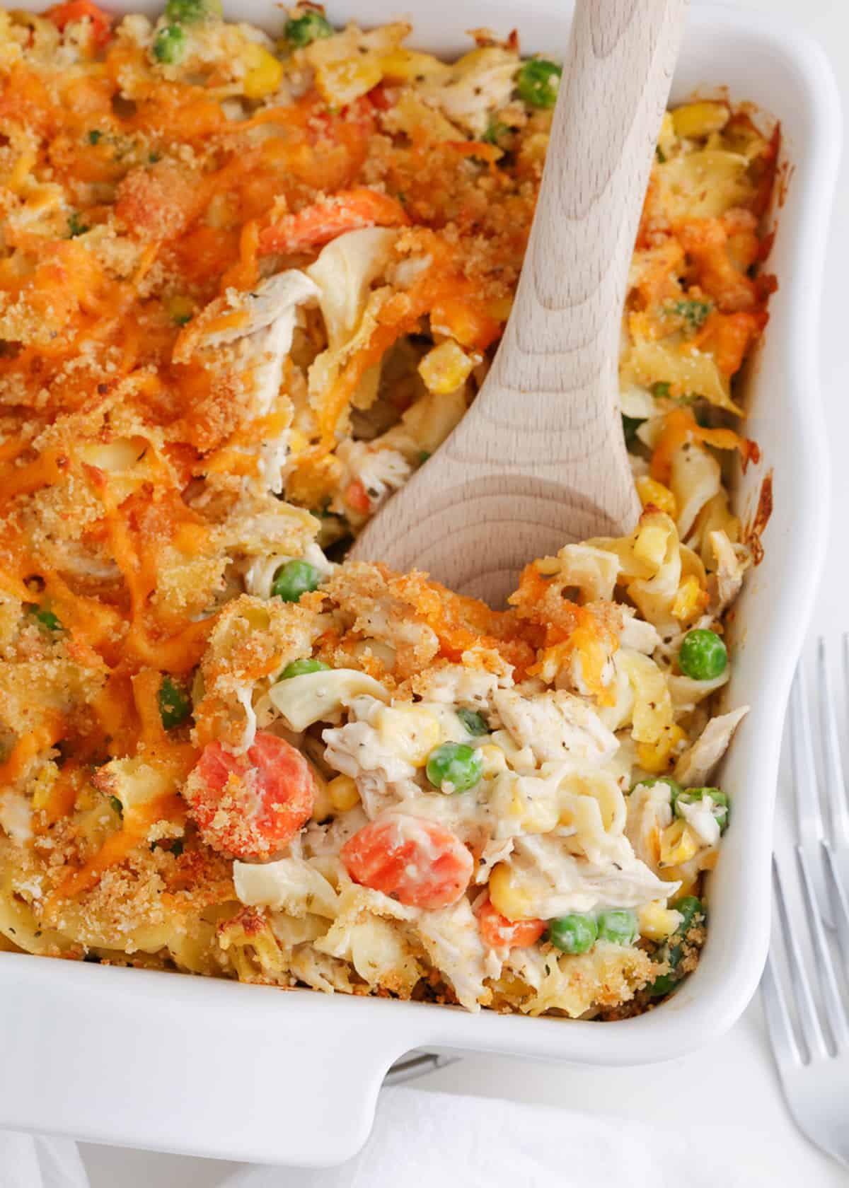 Spoonful of chicken noodle casserole in a white baking dish.