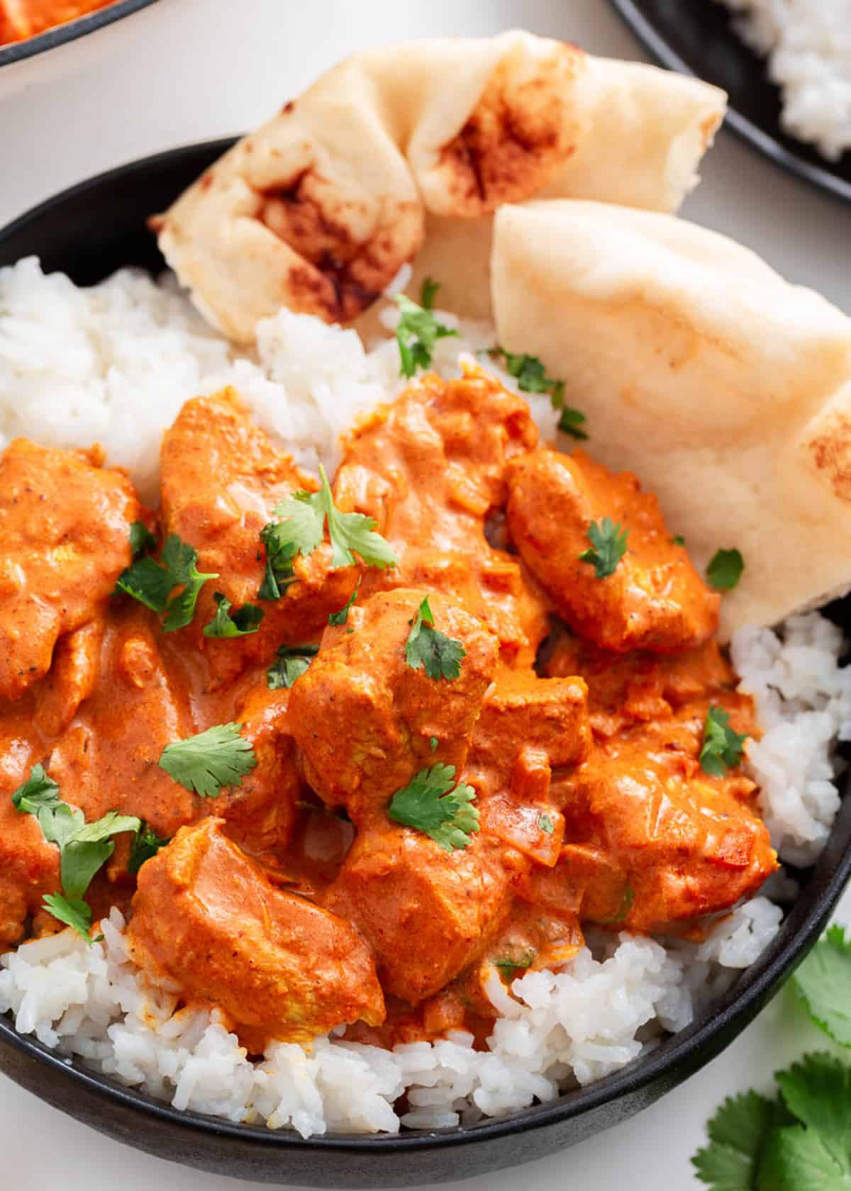 Chicken tikka masala with rice and pita in a bowl.