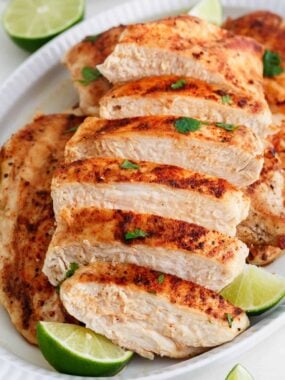 Sliced easy grilled chicken recipe with a lime wedge.