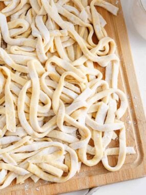Egg noodles on a wooden board.