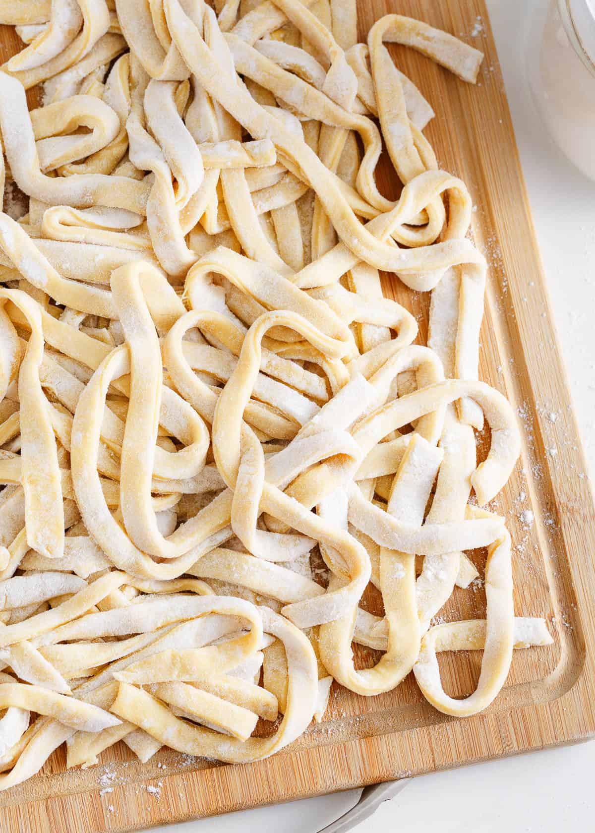 Egg noodles on a wooden board.