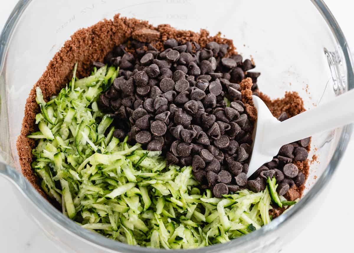 Folding shredded zucchini and chocolate chips into the brownie batter.